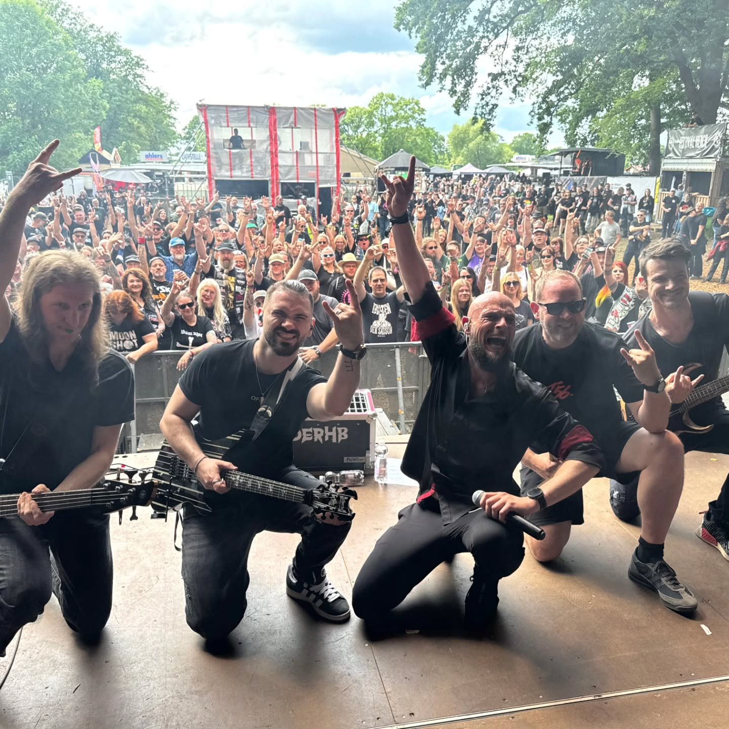 DERHB kniet vor einer vollen Festivalmenge, die Menge zeigt Hörner.